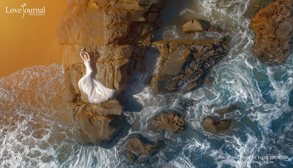 wedding photographer in Melbourne aerial shot of the bride lying on the rock at beach