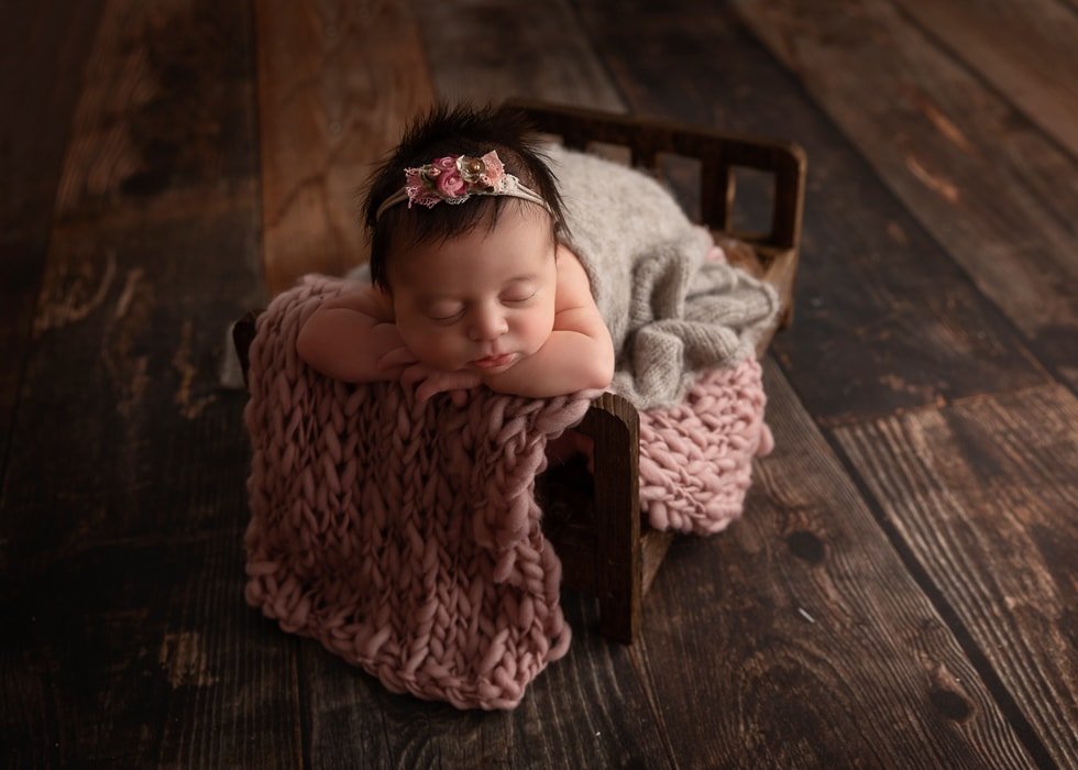 baby photography Sydney newborn is sleeping on a cot with a floral headband