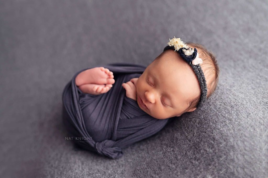 Sydney newborn photography baby is sleeping in dark blue blanket and flower headband