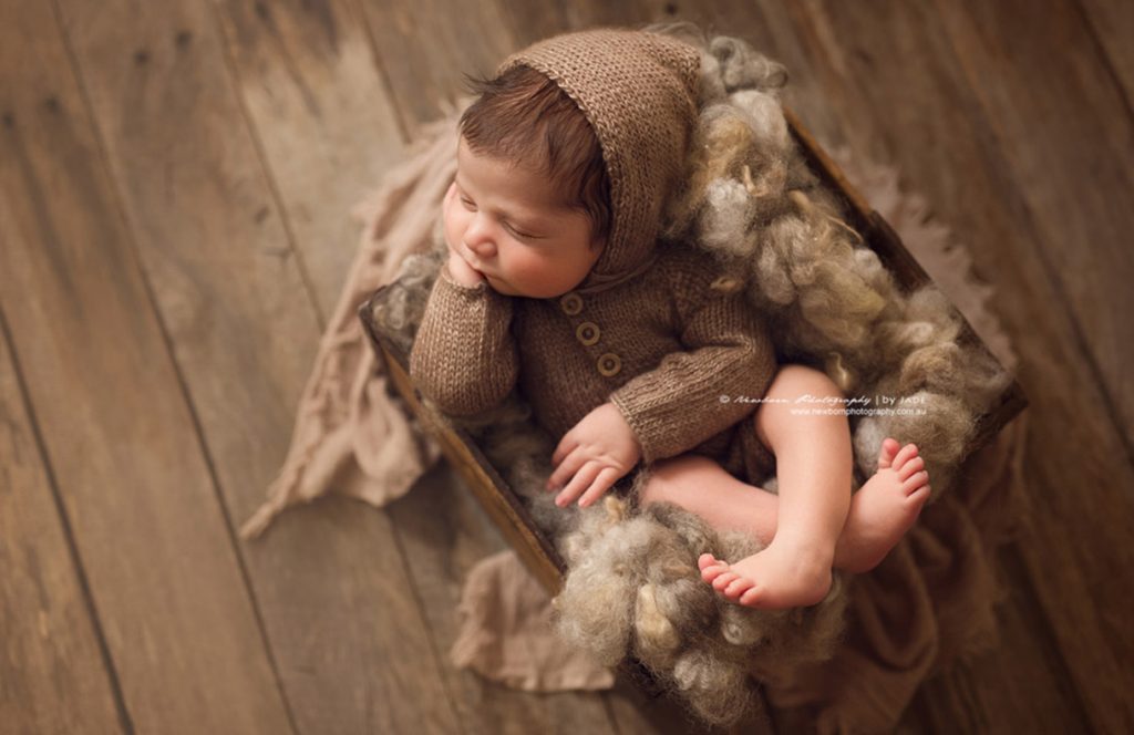 newborn photographer Sydney newborn is sleeping in a brown cot