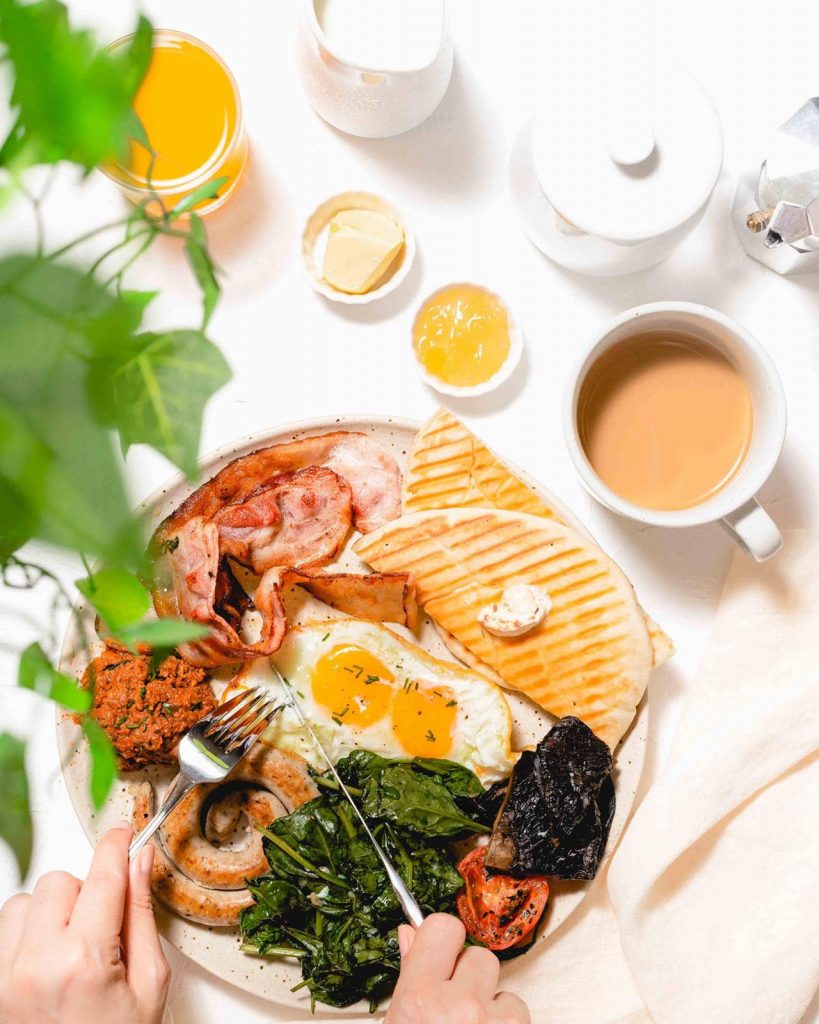 food styling singapore a plate of bacon, eggs, pancakes and spinach which also a cup of tea next to it