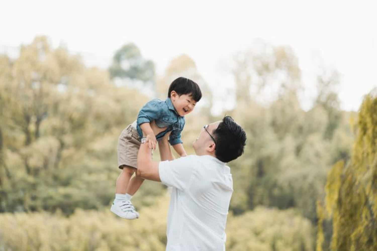 family photoshoot singapore father is holding his son up and both of them are smiling at each other