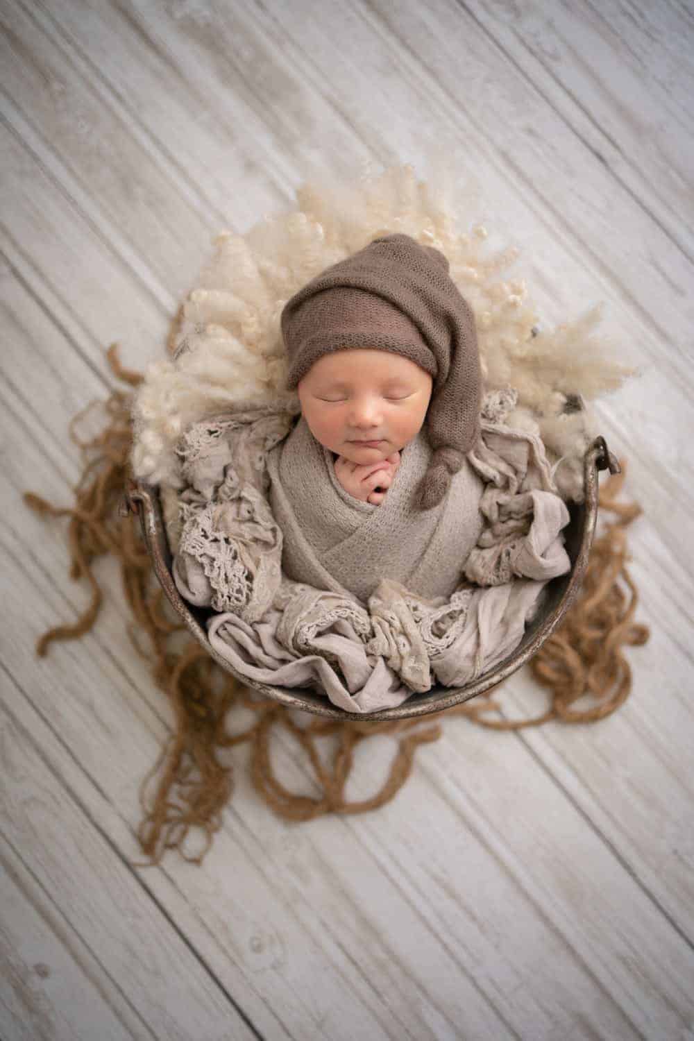 photoshoot for baby singapore newborn wrapped around a brown blanket and placed in basket