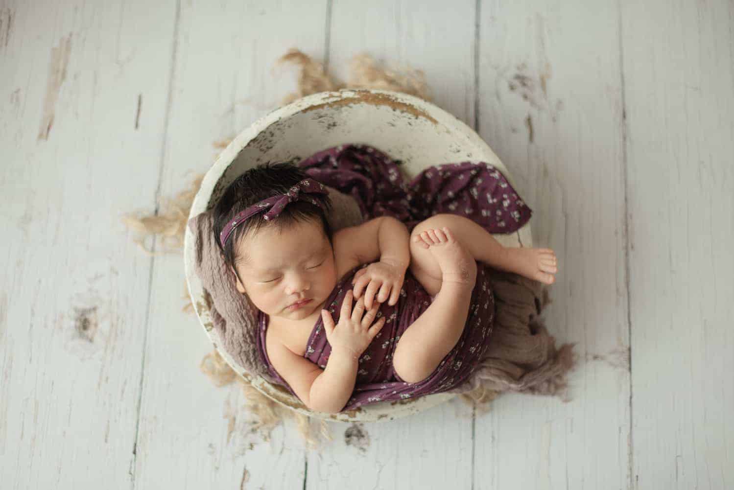 newborn photography singapore curled up baby is covered with a purple blanket