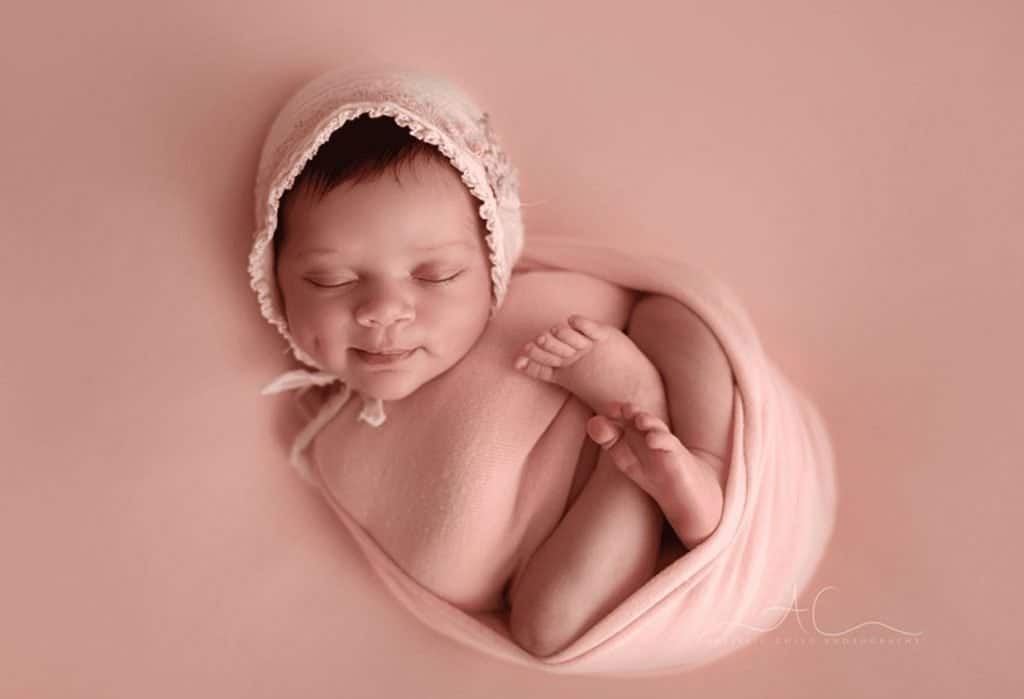 newborn photography London baby is sleeping with a pink wrap