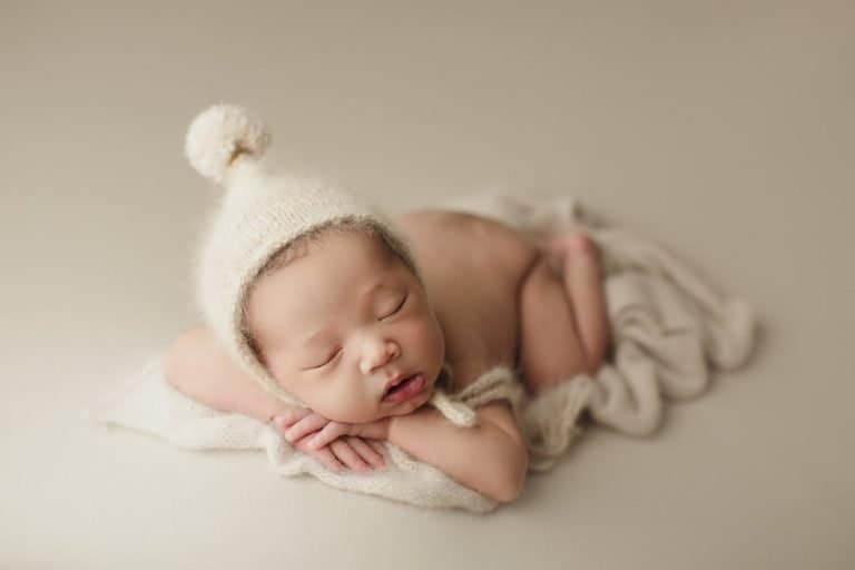 Newborn Photographers in London. A newborn baby sleeping on a white blanket.