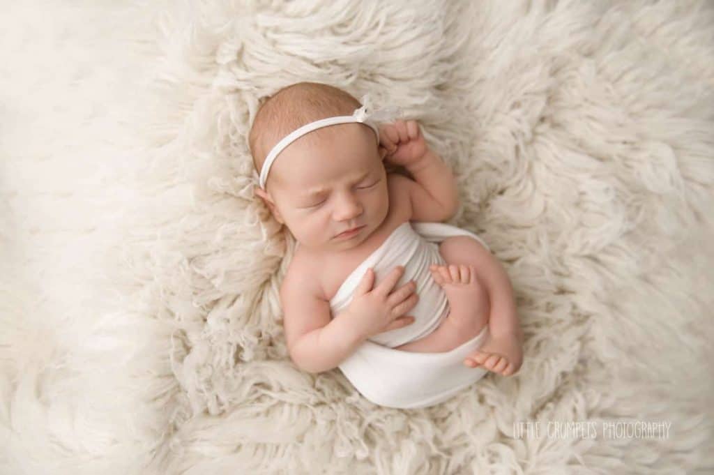newborn photographers London baby is sleeping on white fur bed