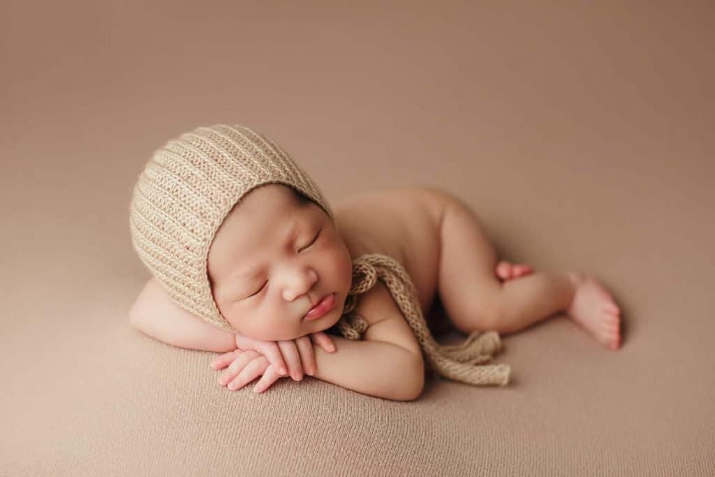 London newborn photography baby is sleeping with beige headwar