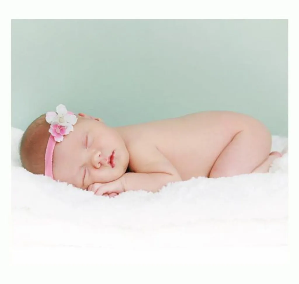 London newborn photography baby is sleeping with a pink deadband infront of a green background