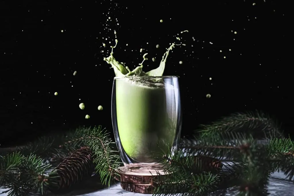 A green smoothie with a splash of liquid on a black background captured by food photographers in Toronto.