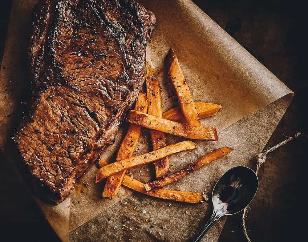 A visually appealing food photograph featuring a steak with sweet potato fries in Toronto.