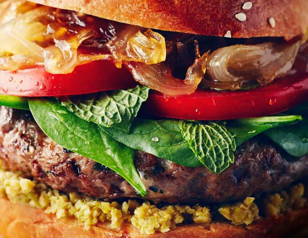 A burger with spinach, tomatoes and onions captured by food photographers in Toronto.