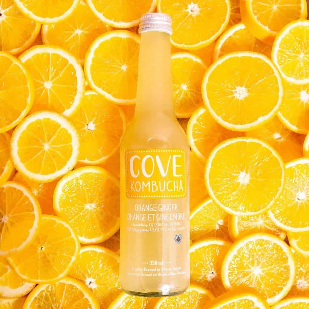 A bottle of cove kombucha surrounded by orange slices captured by food photographers in Toronto.