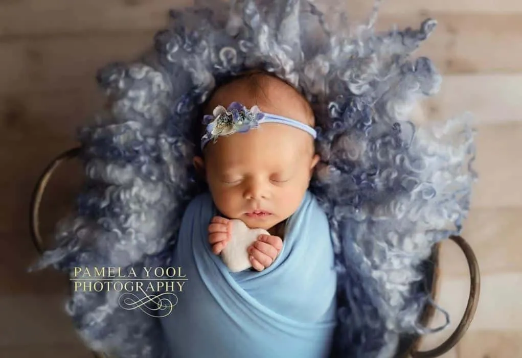A newborn baby sleeping in a blue wrap captured by newborn photographers in Toronto.