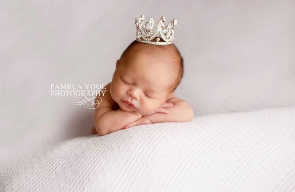 A newborn wearing a tiara laying on a blanket in Toronto.