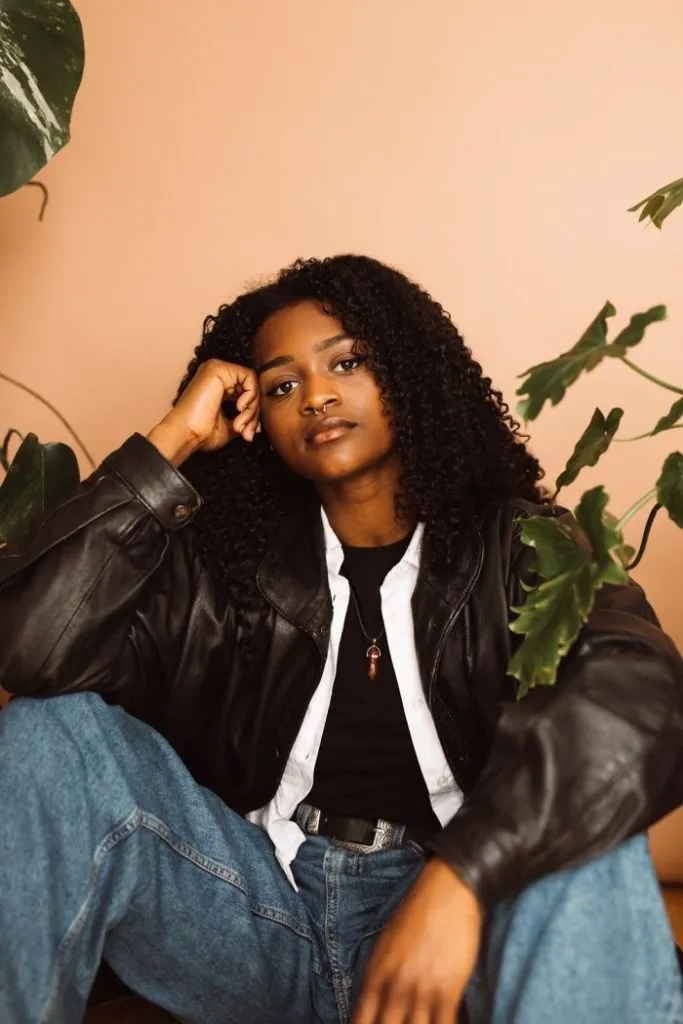 A black woman wearing a leather jacket and jeans photographed by portrait photographers in London.